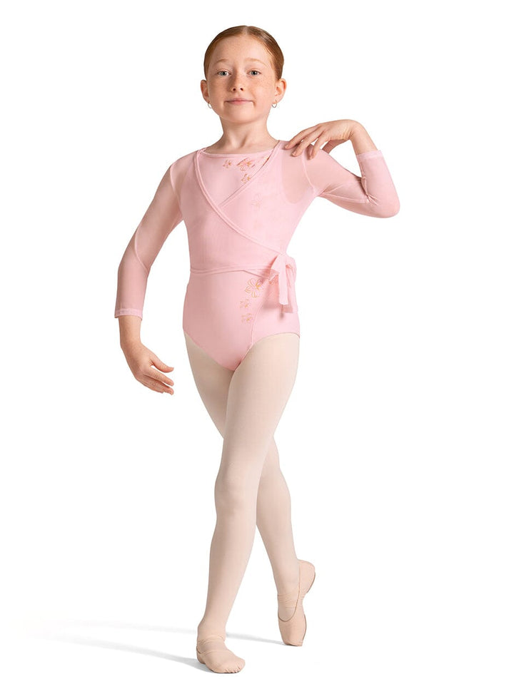 Young girl in a pink ballet leotard and beige tights on a white background
