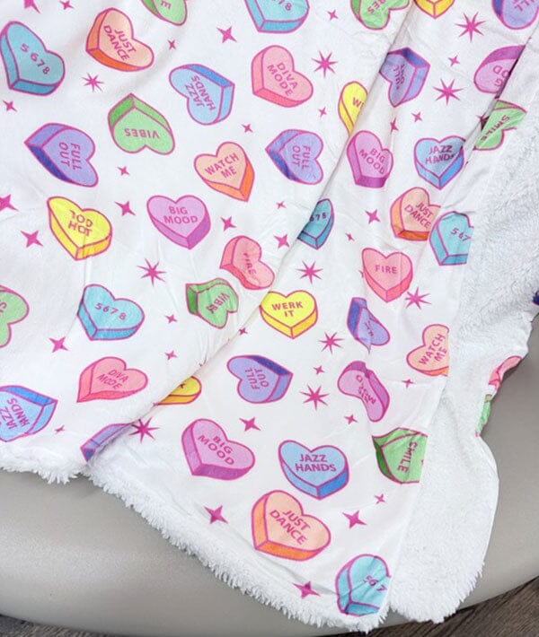 Colorful candy heart pattern on a white blanket with pink stars.