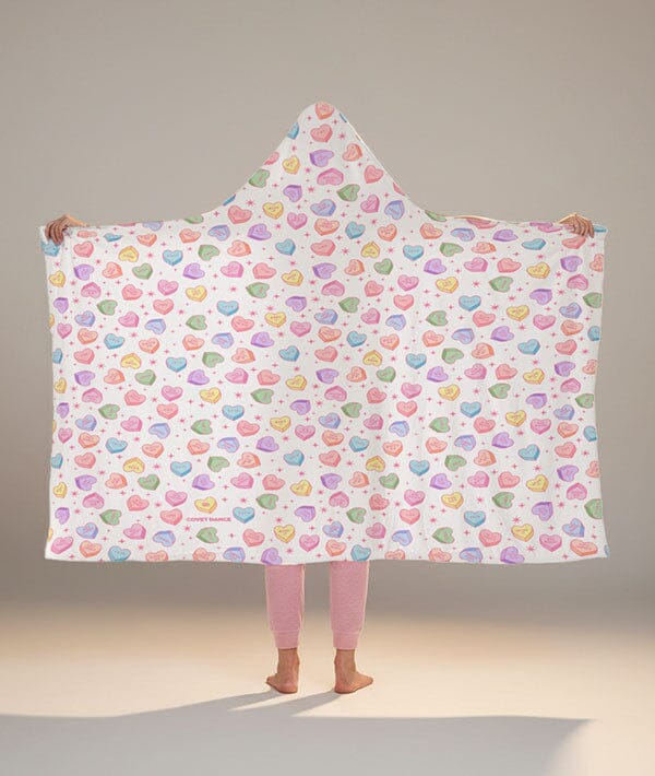 Person wearing a colorful heart-patterned hooded blanket against a neutral background