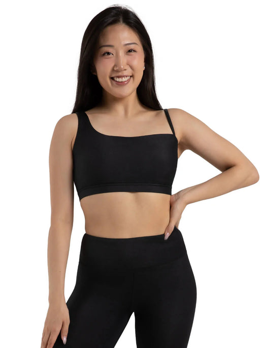 Woman wearing a black sports bra and leggings on a white background