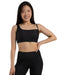 Woman wearing a black sports bra and leggings on a white background