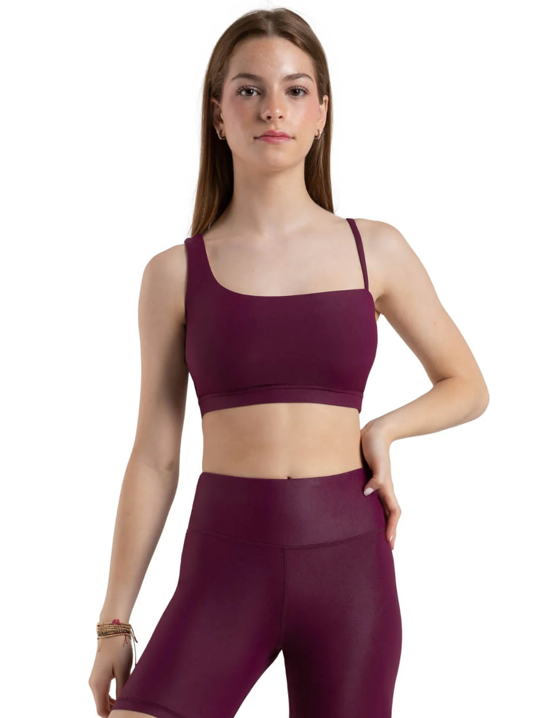 Woman wearing a maroon sports bra and leggings on a white background