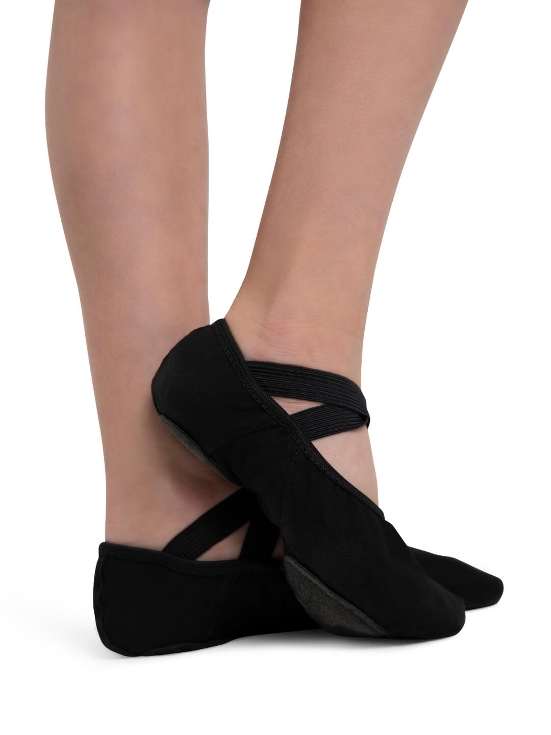 Black ballet shoes worn by a person on a white background