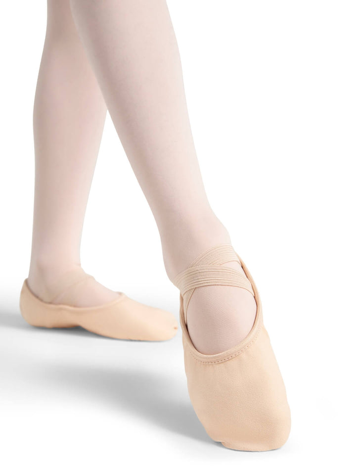 Ballet shoes worn with beige tights on a white background