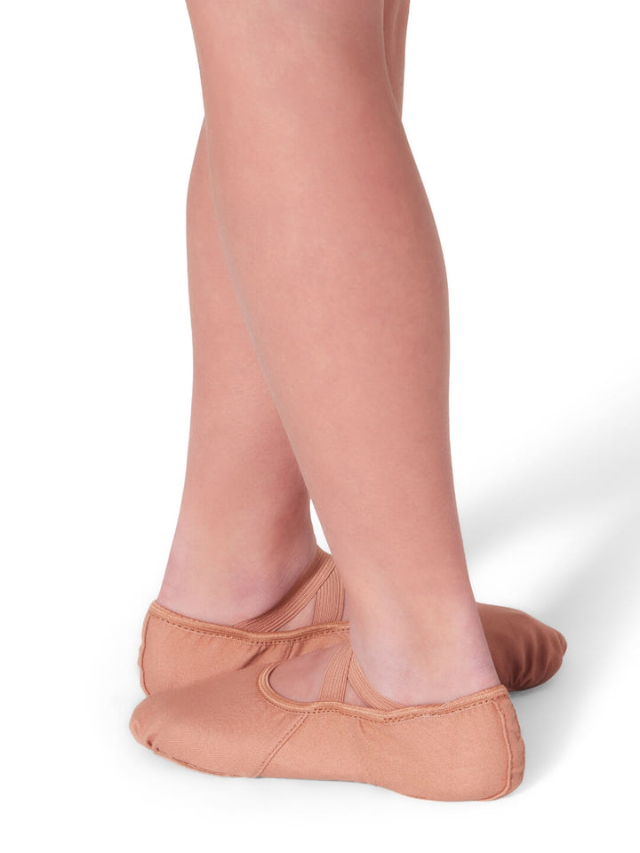 Ballet shoes worn with sheer tights on a white background