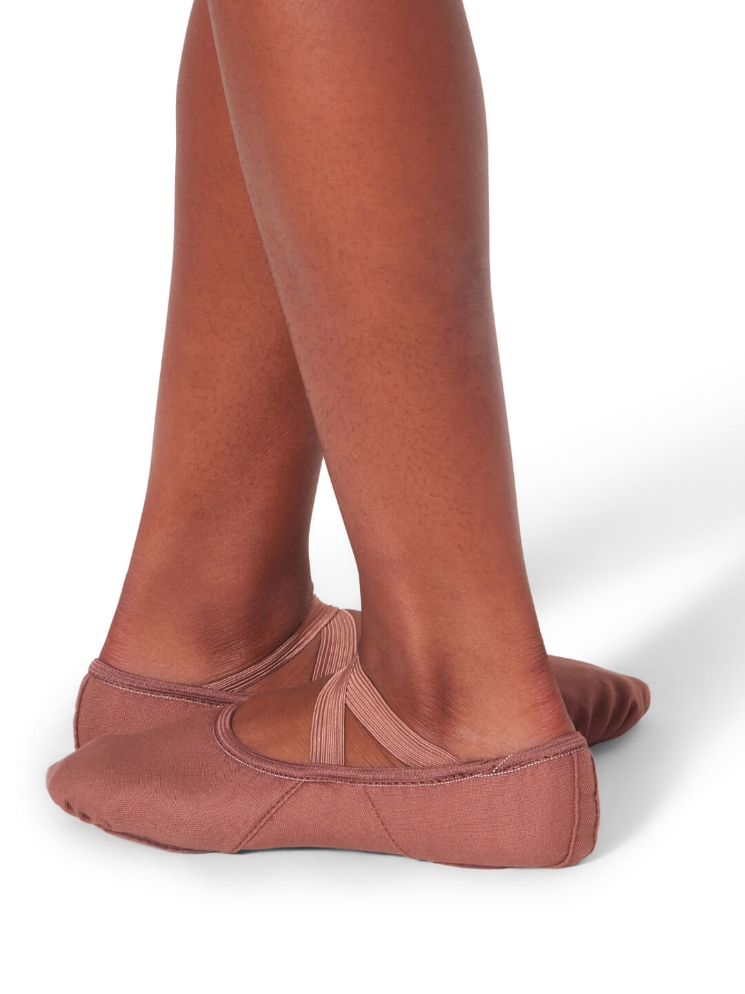 Brown ballet shoes worn with tights on a white background