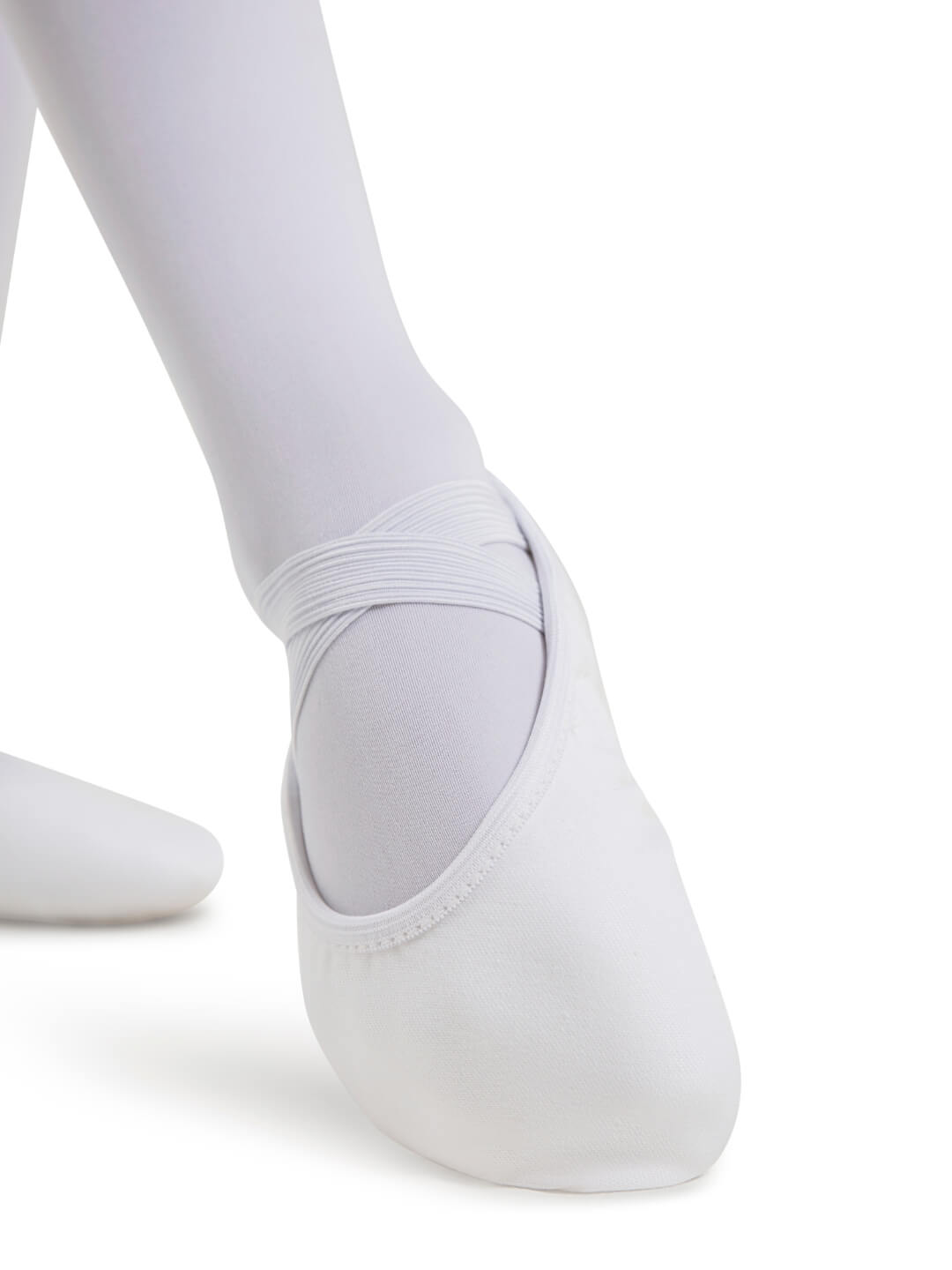White ballet shoes worn with white tights on a white background