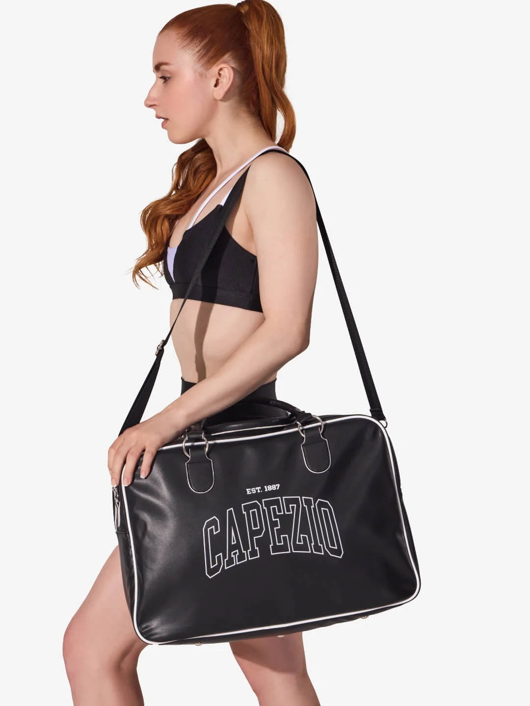 Person holding a black Capezio bag against a white background