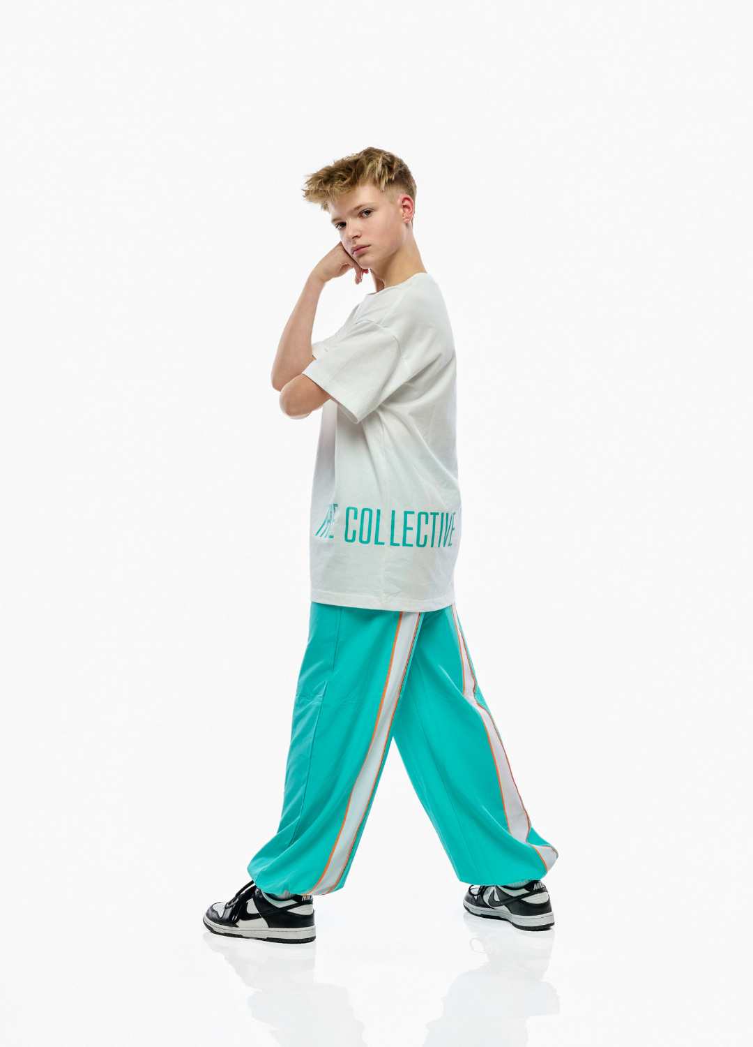 Person wearing a white t-shirt and teal pants with a brand logo on a white background