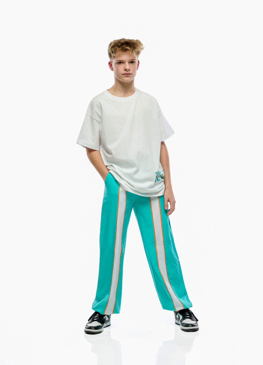 Person wearing a white t-shirt and teal pants with white stripes on a white background