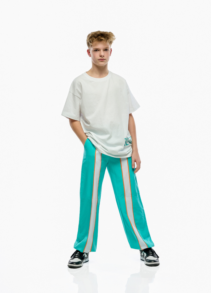 Person wearing a white t-shirt and teal pants with white stripes on a white background