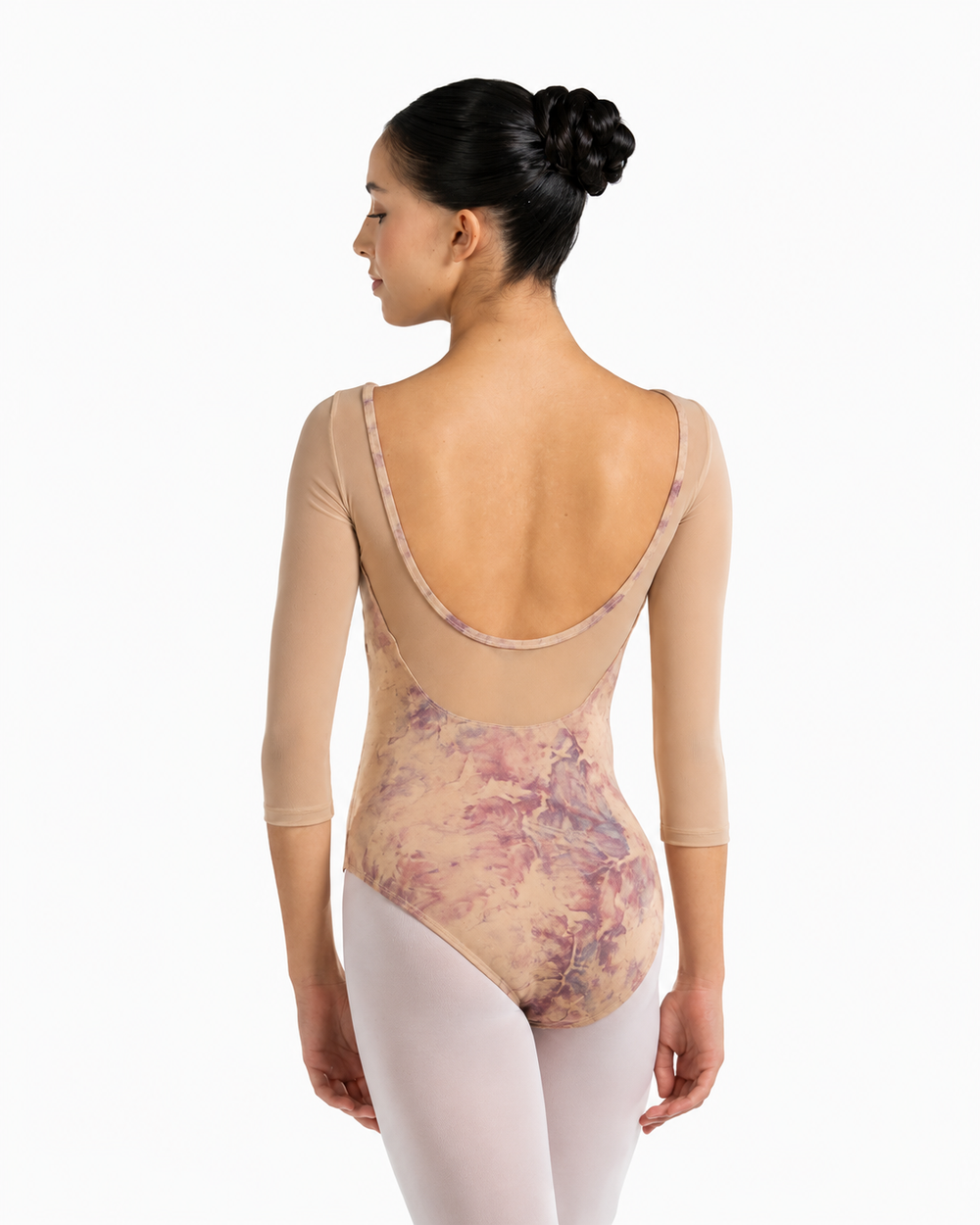 A woman modeling a three-quarter sleeve leotard from the back, showing a dusty pink and purple floral pattern over a nude base, paired with light pink tights against a white background.