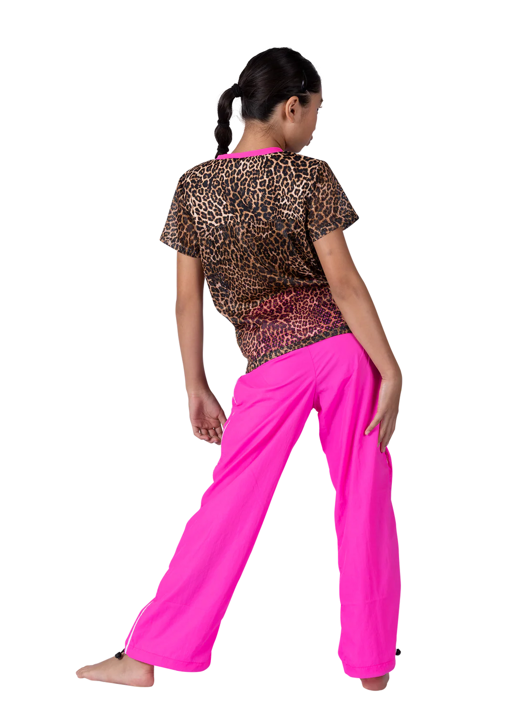 Woman wearing a leopard print top and bright pink pants on a white background