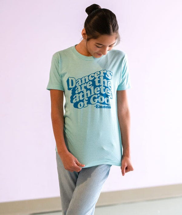 Person wearing a light blue t-shirt with text Dancers are the athletes of God in a dance studio.