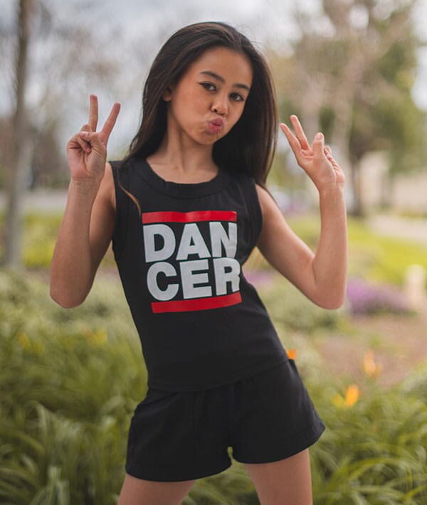 Person wearing a black sleeveless top with 'DANCER' printed on it, standing outdoors.