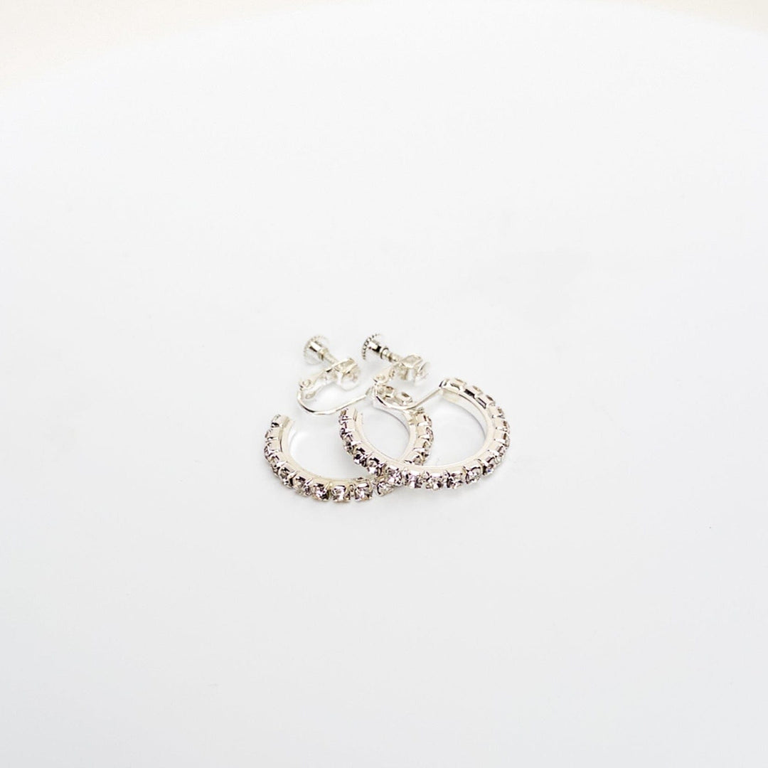 Silver hoop earrings with pink gemstones on a light gray background