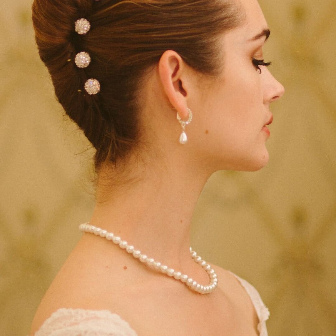 Woman wearing a pearl necklace and earrings with a blurred background