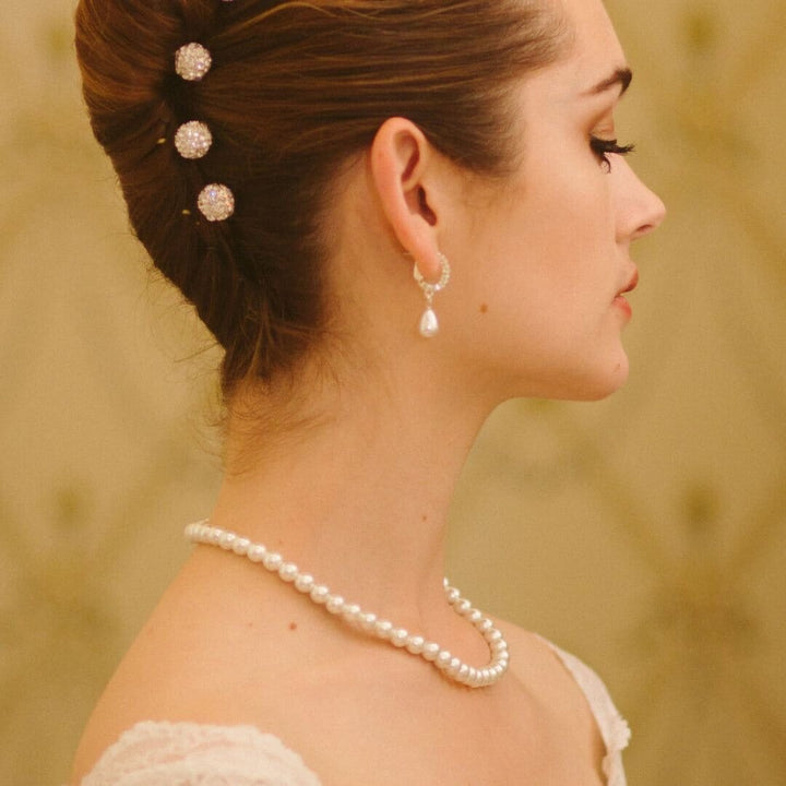 Woman wearing a pearl necklace and earrings with a blurred background