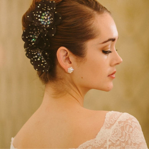 Woman with decorative hairpiece and earrings against a neutral background