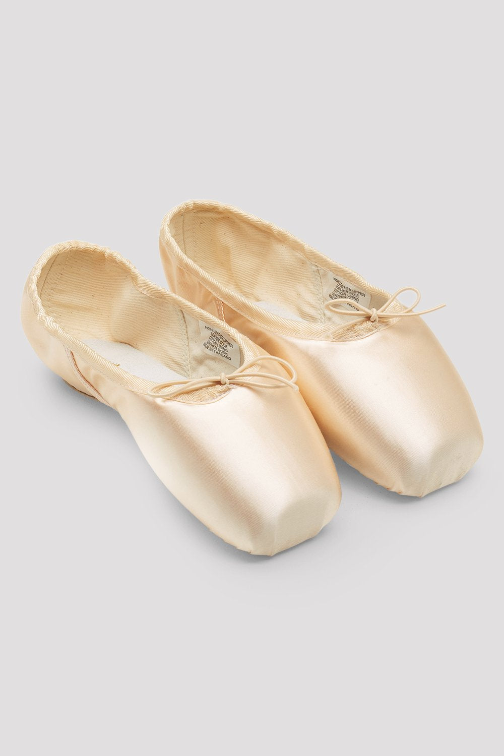 Pair of beige ballet shoes on a light gray background