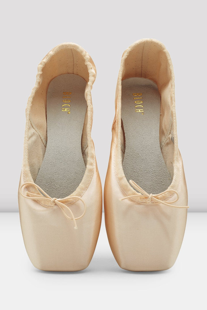 Pair of beige ballet shoes with ribbons on a light gray background