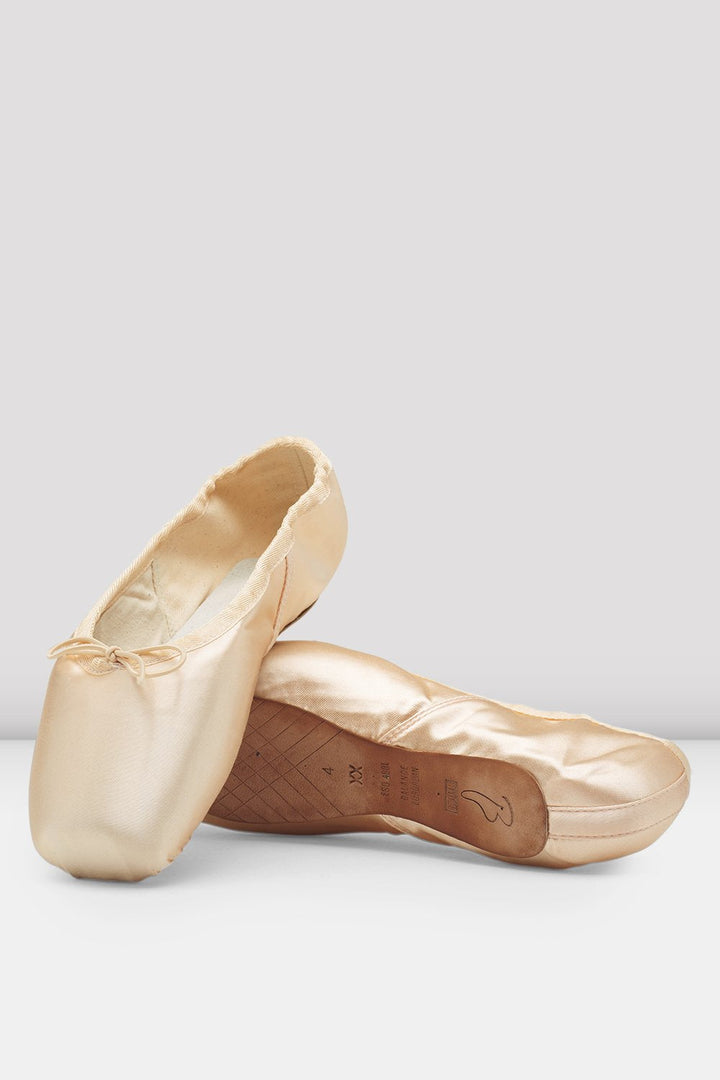 Pair of gold ballet shoes on a light gray background