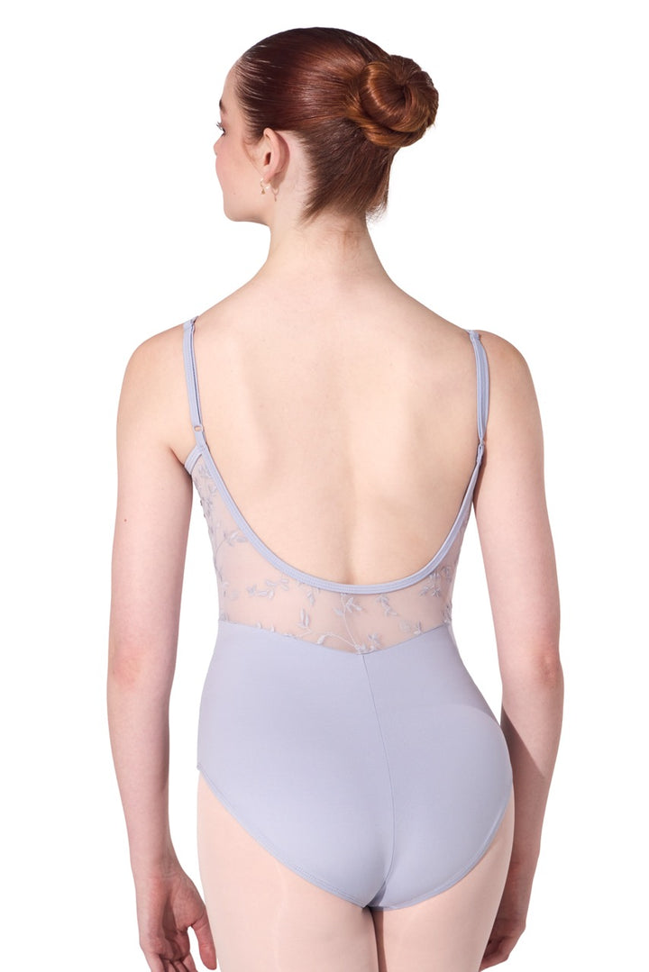 A woman shown from the back wearing a light lavender-gray leotard with sheer lace detailing along the open back, set against a plain white background.