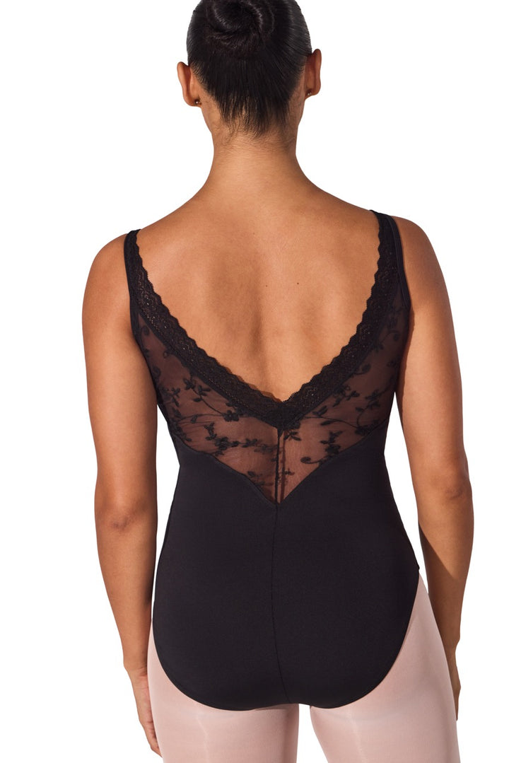 Rear view of a model wearing a black lace and mesh leotard with a deep V-back and lace trim, paired with light pink tights against a white background.