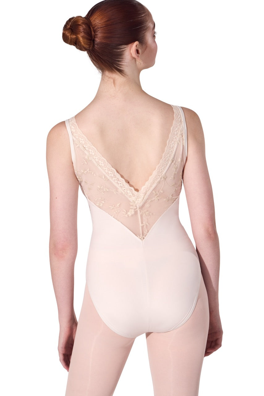 A woman modeling a light beige or nude-colored leotard from the back, showing a lace-trimmed open back and smooth fabric below, against a plain white background.