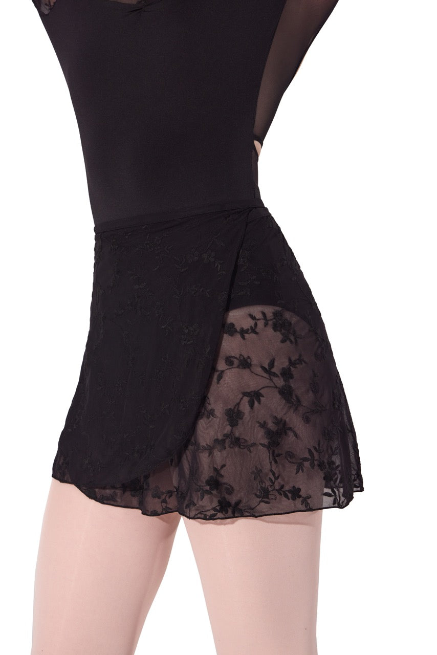 A close-up of a black dance leotard skirt featuring a sheer floral lace overlay and a solid black mesh bodice, shown on a model against a white background.