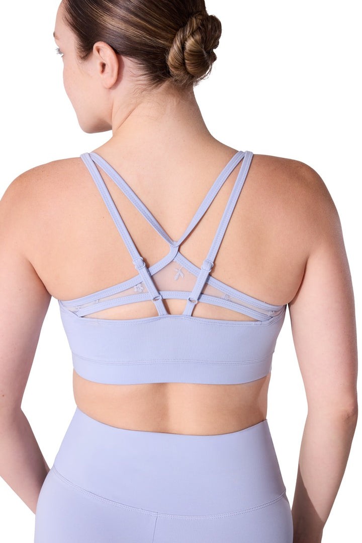 A woman shown from the back wearing a light periwinkle blue sports bra with multiple crisscrossing straps and matching high-waisted leggings against a white background.