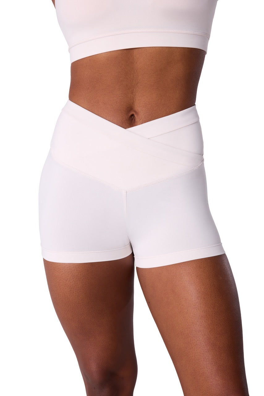 White high-waisted athletic shorts with a crossover waistband, shown on a model from the waist to mid-thigh against a plain white background.