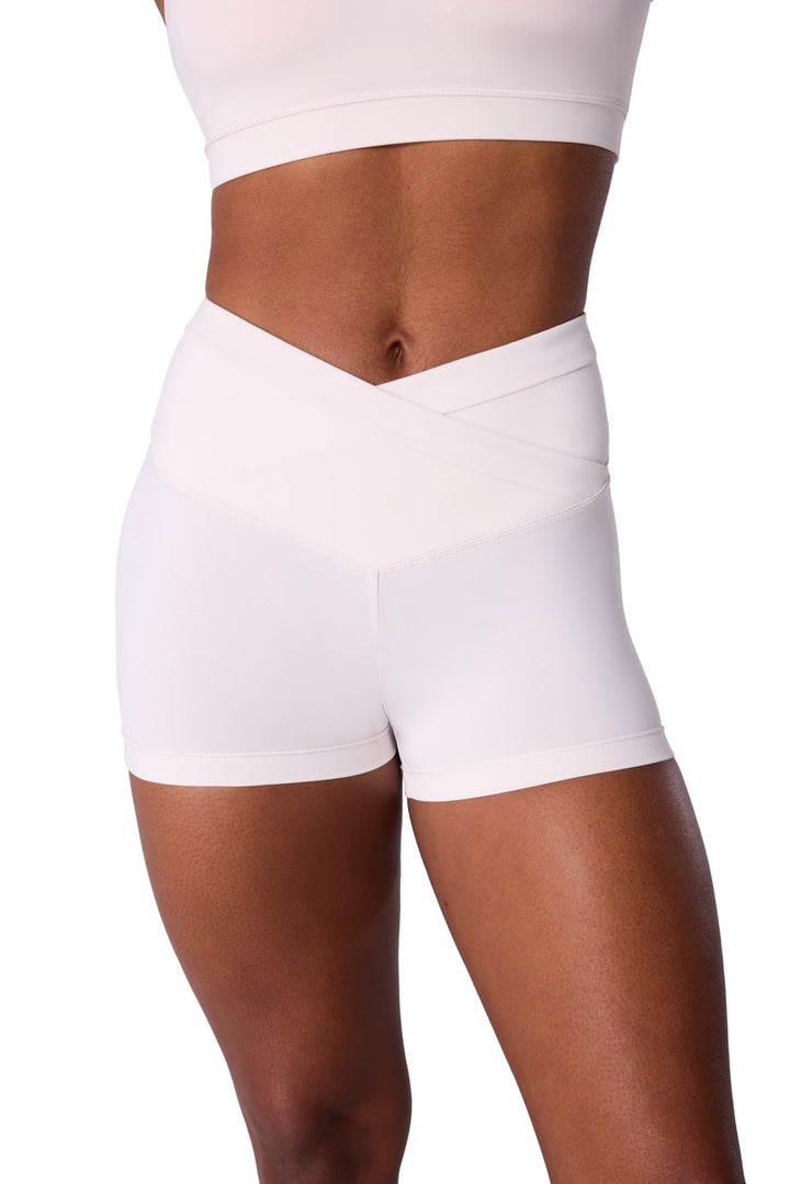 White high-waisted athletic shorts with a crossover waistband, shown on a model from the waist to mid-thigh against a plain white background.