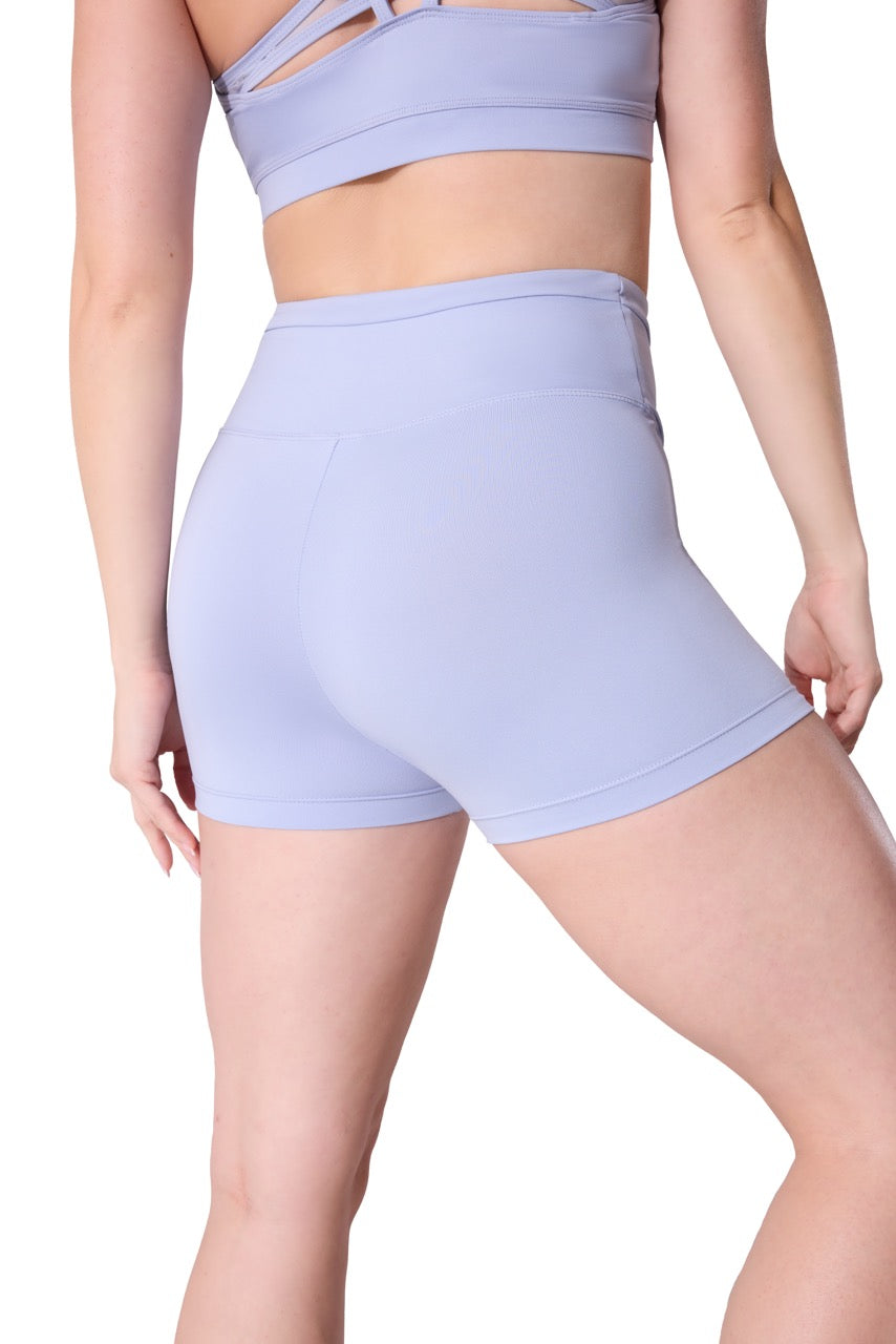 A model shown from the back wearing a matching lavender athletic set consisting of high-waisted shorts and a sports bra, against a plain white background.