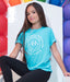 Person wearing a blue t-shirt with text, sitting against a colorful balloon background