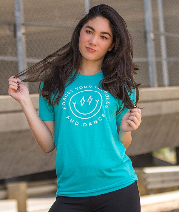 Woman wearing a teal t-shirt with a motivational quote, standing outdoors.