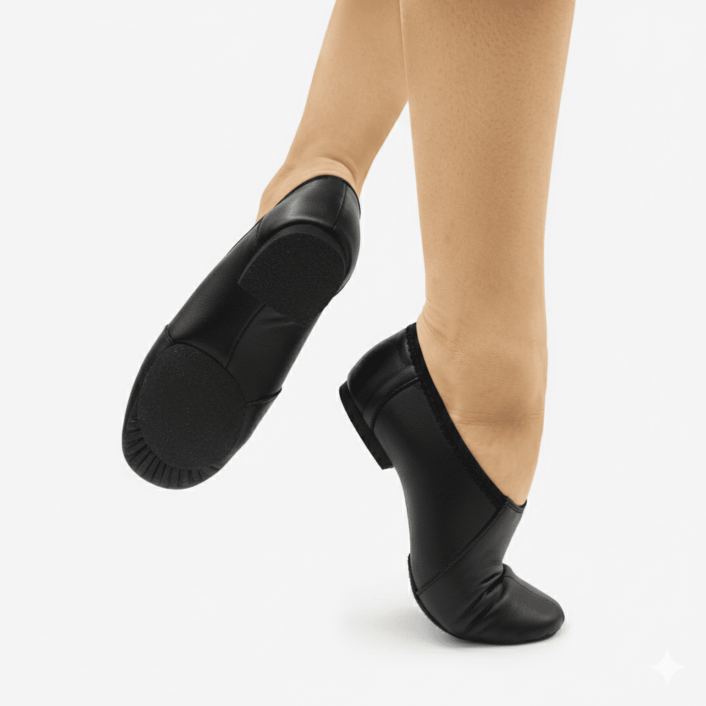 Black dance shoes worn with beige tights on a white background