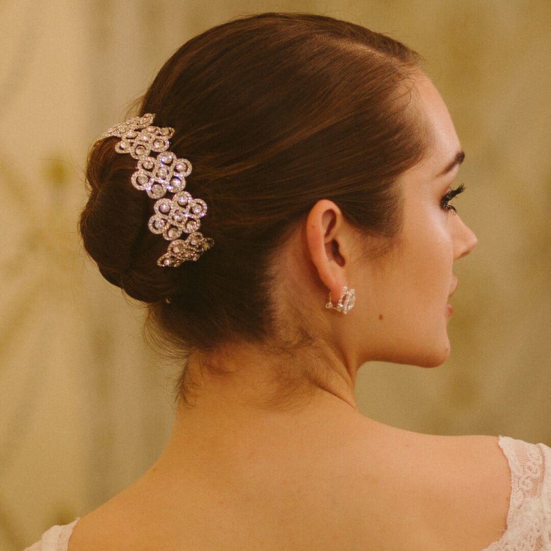 Woman wearing a decorative hair clip and matching earrings against a neutral background