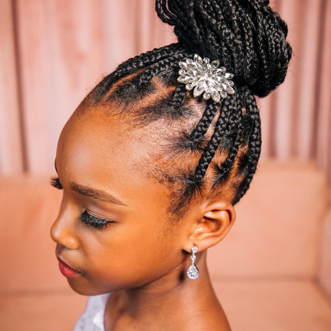 Young girl with braided hair wearing a decorative hair clip against a pink background