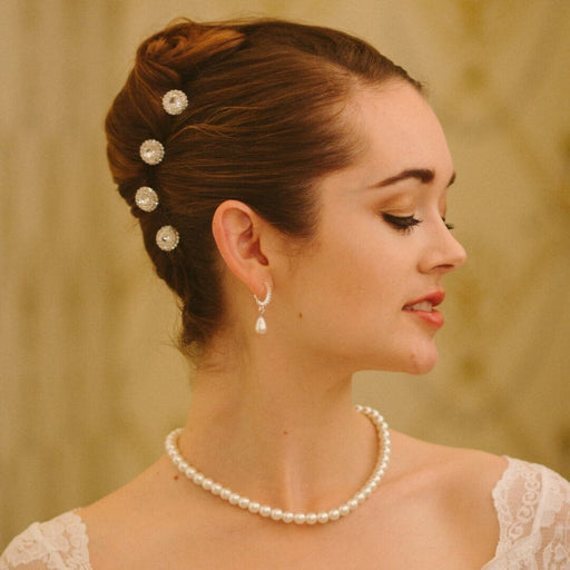 Woman with styled hair and pearl necklace against a beige background