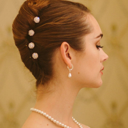 Woman with styled hair and pearl accessories against a blurred background