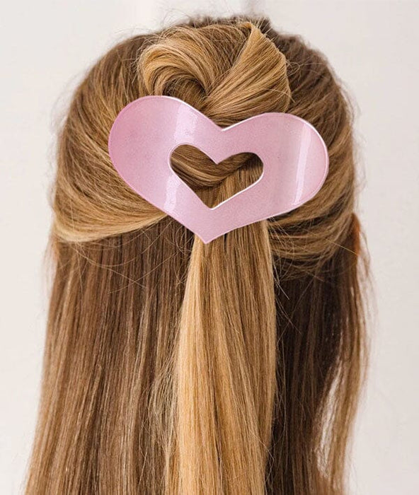 Heart-shaped hair clip in a person's hair on a plain background