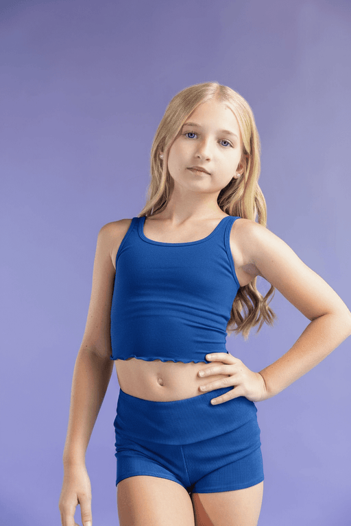 Young girl wearing a blue athletic outfit against a purple background