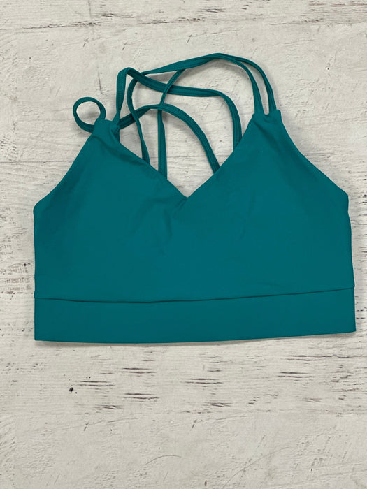 Teal sports bra with thin straps on a light wooden surface