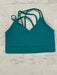 Teal sports bra with thin straps on a light wooden surface