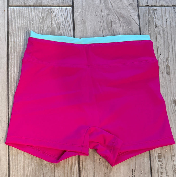Pink shorts with a blue waistband on a wooden floor