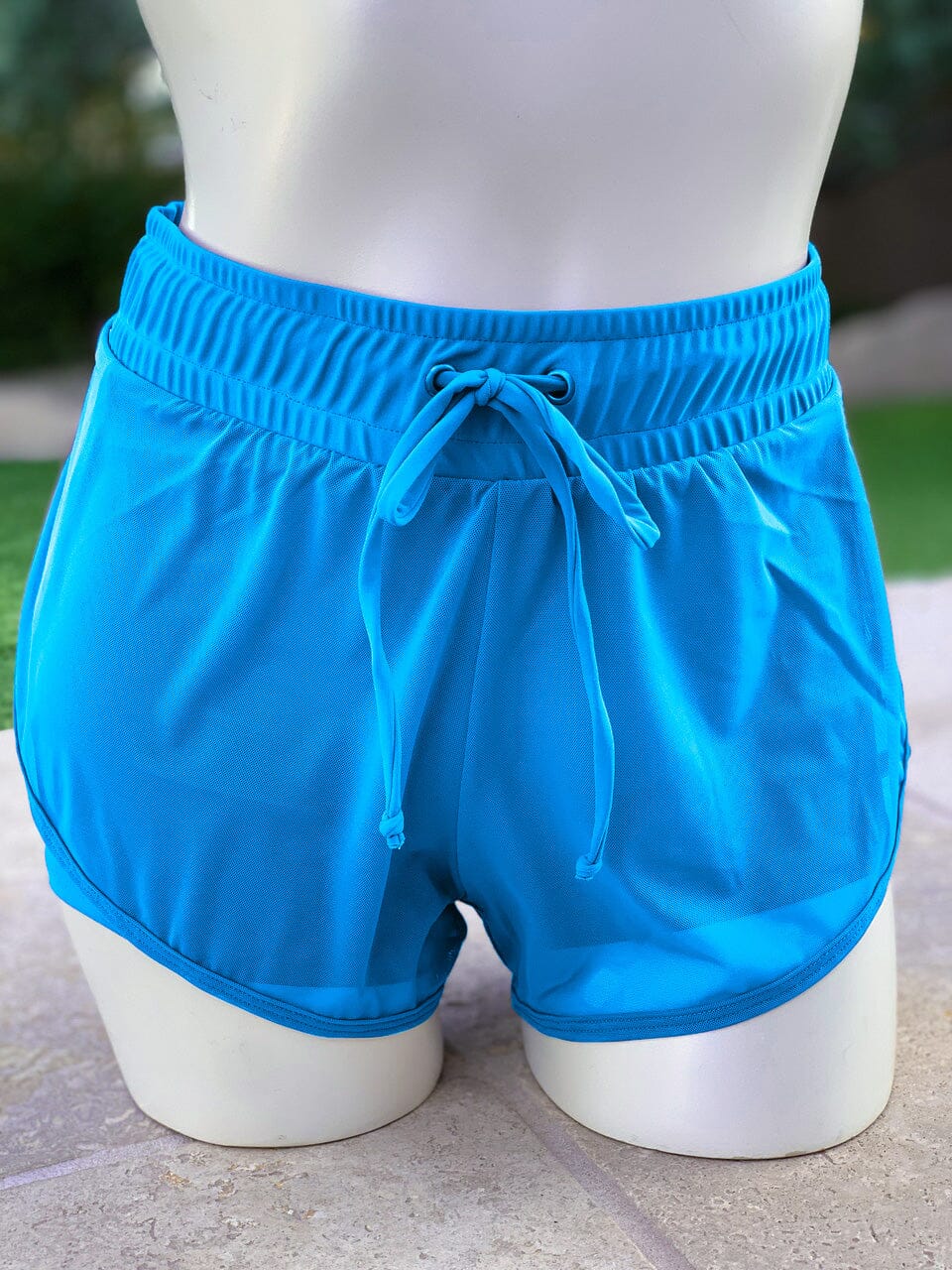 Blue shorts on a mannequin against a blurred outdoor background
