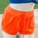 Orange shorts with a drawstring on a neutral background