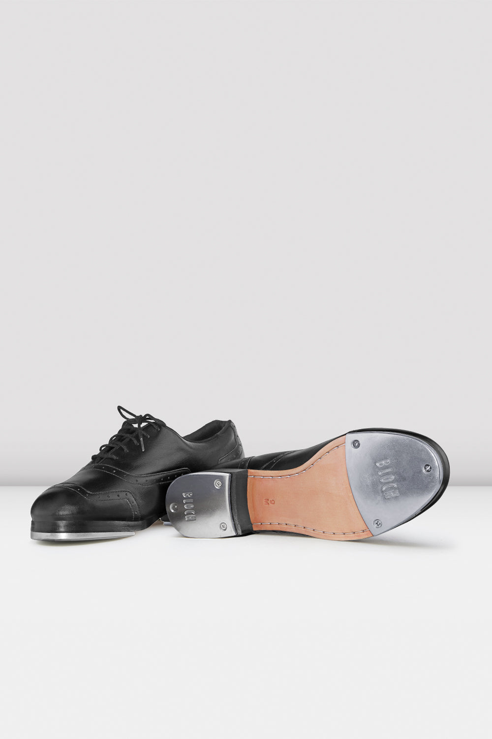Black tap dance shoes with a white sole on a white background