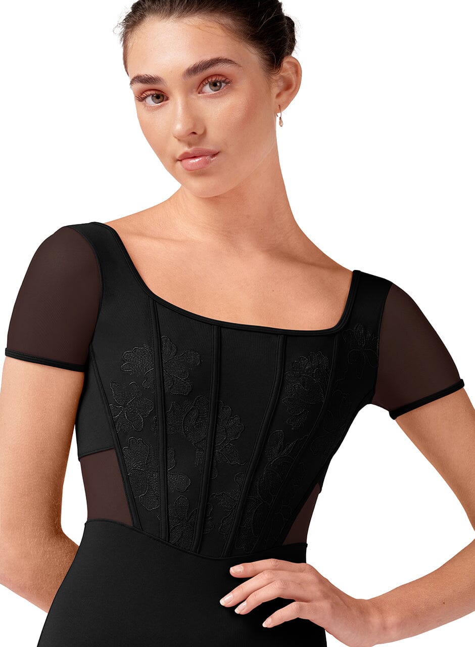 Woman wearing a black dress with sheer sleeves on a white background